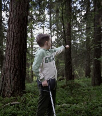 A boy with a cane in the woods